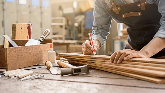 Carpenter working with equipment on wooden table in carpentry shop. woman works in a carpentry shop.