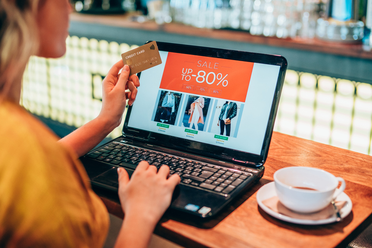 Young woman shopping online in cafe using laptop and credit card.